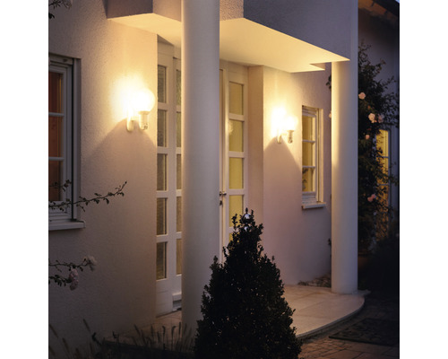 Hausfassade mit beleuchteten Wandleuchten neben der Eingangstür