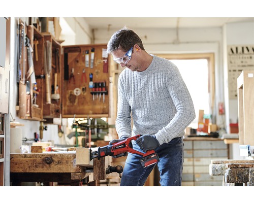 Mann sägt Holz mit einer Einhell Akku-Säbelsäge in einer Werkstatt