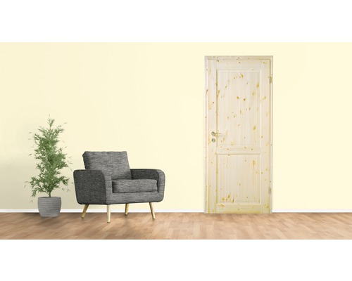Holztür mit zwei Paneelen, grauer Sessel und Topfpflanze in einem hellen Raum.