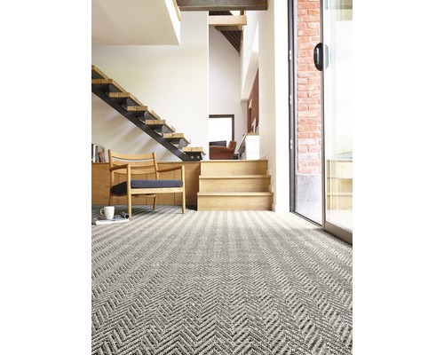 Heller Raum mit gemustertem Teppich, Treppe und Stuhl