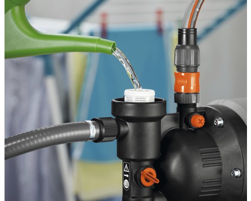 Gartenpumpe wird mit einer Gießkanne befüllt