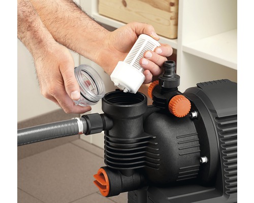 Person setzt Filter in eine Gartenpumpe ein