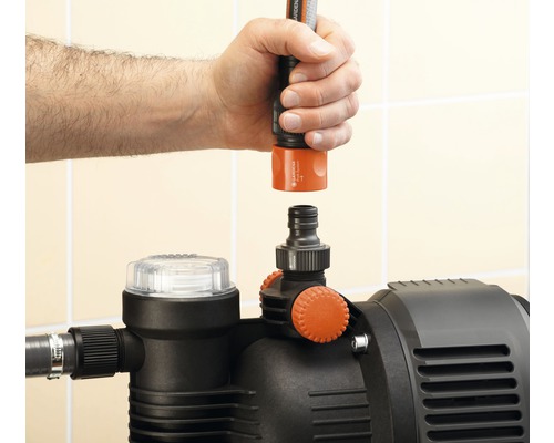 Hand schliesst Gartenschlauch an Gartenpumpe an