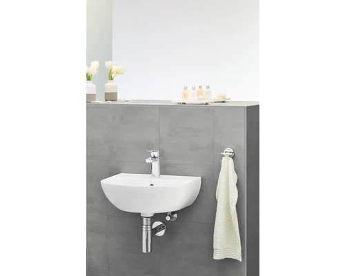 Aufhängewaschbecken im Badezimmer mit Armatur, Handtuch und Badezimmerutensilien