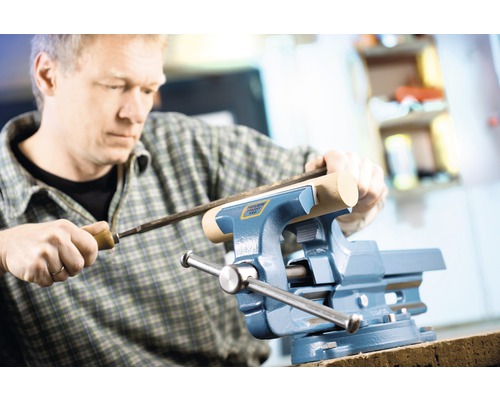 Mann bearbeitet ein Werkstück mit einer Feile in einem Schraubstock