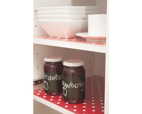 Küchenschrank mit Geschirr und Marmeladengläsern auf Regalfolie mit Punktmuster