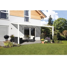 Terrasse mit Terrassenüberdachung, Gartenmöbeln und Grill auf Rasenfläche vor einem Wohnhaus
