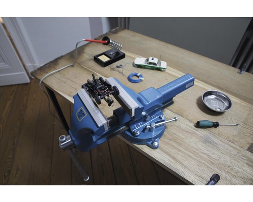 Werkbank mit Schraubstock, Lötkolben und Modellauto