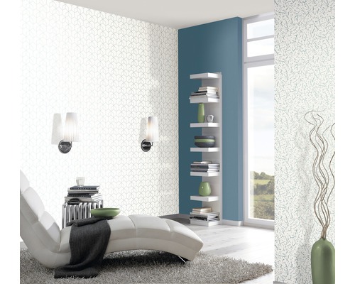 Wohnraum mit geometrischer Tapete, Liege und Bücherregal.