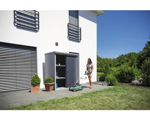 Gartenszene mit Geräteschrank, Rasenmäher und Frau