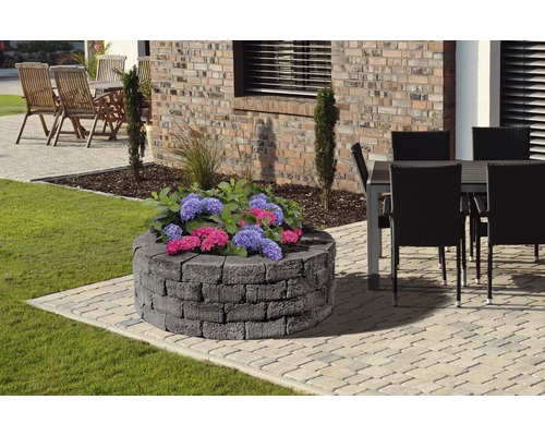 Runde Kräuterspirale aus Stein mit Pflanzen im Garten