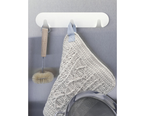 Küchenszene mit Geschirrbürste, Topflappen und Sieb an einer Hängeleiste