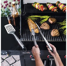 Person grillt Steaks, Spargel und Gemüsespieße auf einem Grill mit Grillbesteck und Saucen