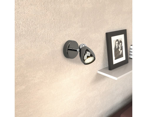 Schwarze Wandleuchte mit LED-Licht und verstellbarem Kopf neben einem Regal