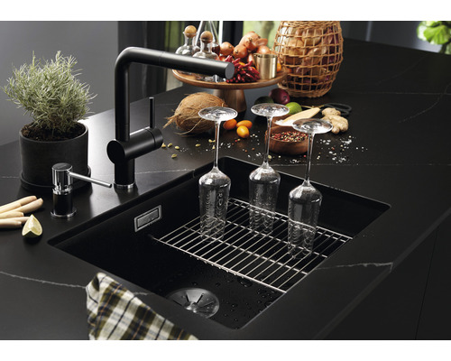 Schwarze Küchenspüle mit Abtropfgitter, Armatur und Spülmittelspender auf einer dunklen Arbeitsplatte