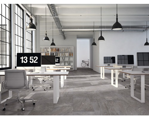 Helles Büro mit Computern, Schreibtischen, Stühlen und einer Bibliothek im Hintergrund