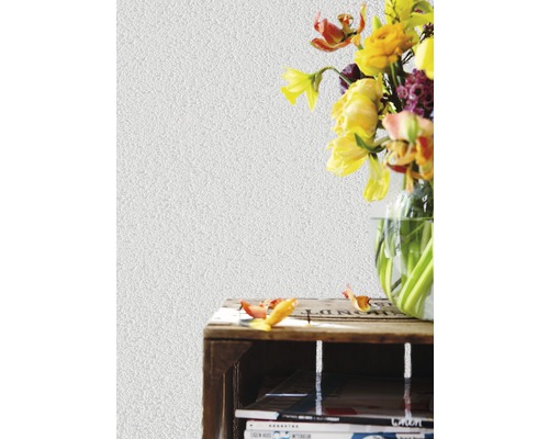 Dekorative Wand mit Putzstruktur neben Blumenstrauß auf einem Regal