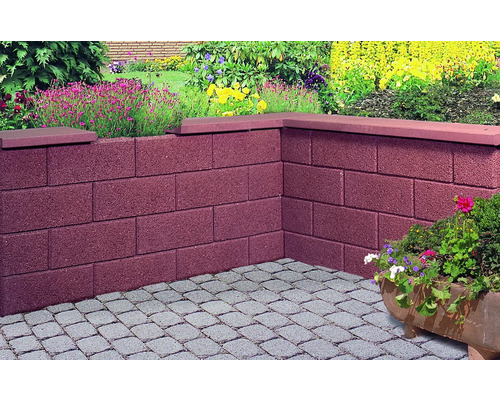 Ecke einer Gartenmauer aus Betonsteinen mit Steinabdeckung und Pflastersteinen im Garten