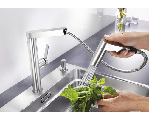 Küchenarmatur mit Brausekopf und Person, die Kräuter wäscht