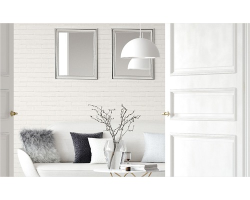 Helles Wohnzimmer mit Sofa, Kissen, Tisch, Dekoration, Lampen, Spiegeln und offener Tür.