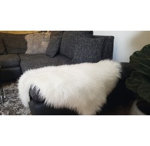 Graues Ecksofa mit Kissen und einem weißen Kunstfellteppich