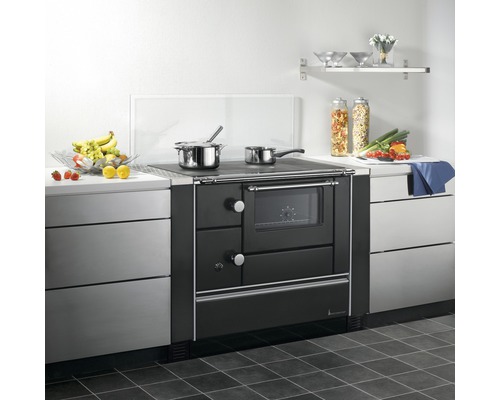 Küchenszene mit einem schwarzen Holzherd zwischen Küchenschränken