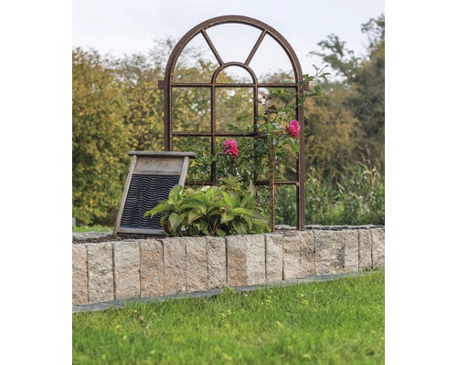 Dekorativer Garten mit Metallfensterrahmen, Waschbrett und Steinmauer.