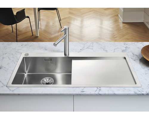 Spüle aus Edelstahl mit Abtropffläche und Armatur auf einer Arbeitsplatte