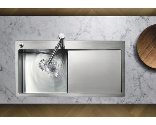 Edelstahlspüle mit Abtropffläche und Wasserhahn auf Marmorarbeitsplatte