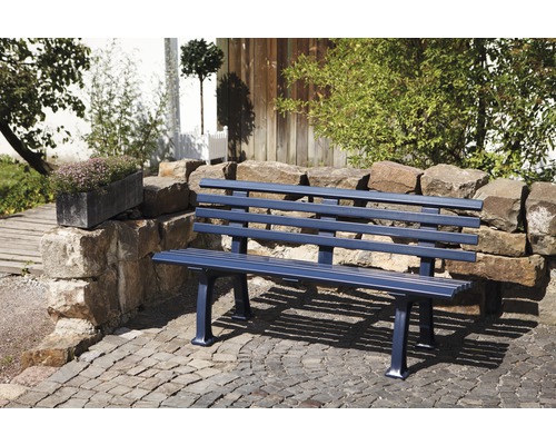 Eine Gartenbank aus Metall steht auf einem gepflasterten Platz in einem Garten.