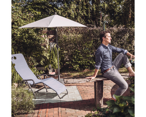 Gartenszene mit Liegestuhl, Sonnenschirm und Mann im Garten