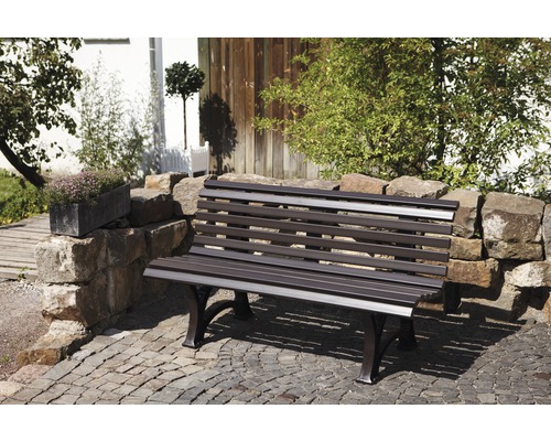 Garten Szene mit Steinmauer und einer Gartenbank aus Metall.