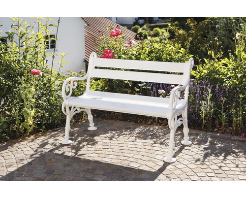 Weiße Gartenbank aus Metall vor Gartenkulisse