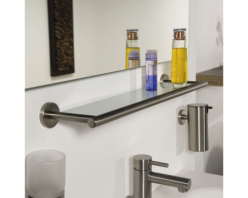 Badezimmeransicht mit Spiegel, Glasablage, Seifenspender und Wasserhahn aus gebürstetem Edelstahl.