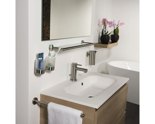 Badezimmer mit Waschtisch, Armatur, Spiegel, Handtuchhalter, Seifenspender und Zahnputzbecher