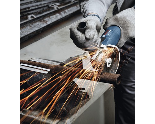 Eine Person schneidet mit einem Winkelschleifer ein Metallrohr, wobei Funken sprühen.
