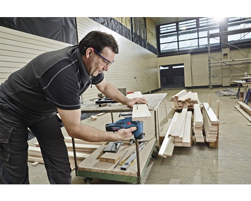 Ein Mann verwendet eine Stichsäge, um ein Holzbrett zu schneiden.