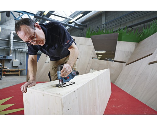 Ein Mann benutzt eine Stichsäge, um Holz zu schneiden. Das Bosch Logo ist sichtbar.