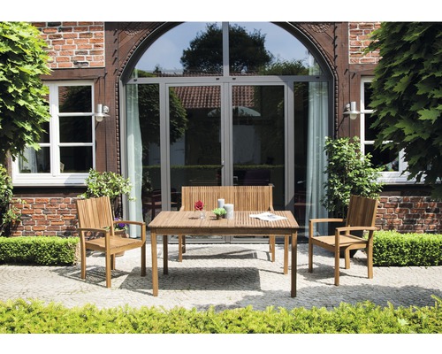 Gartenszene mit Teakholzmöbeln, bestehend aus Tisch, Bank und zwei Stühlen vor einem Haus