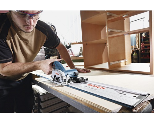 Ein Mann mit Schutzbrille schneidet Holz mit einer Handkreissäge und Führungsschiene von Bosch.