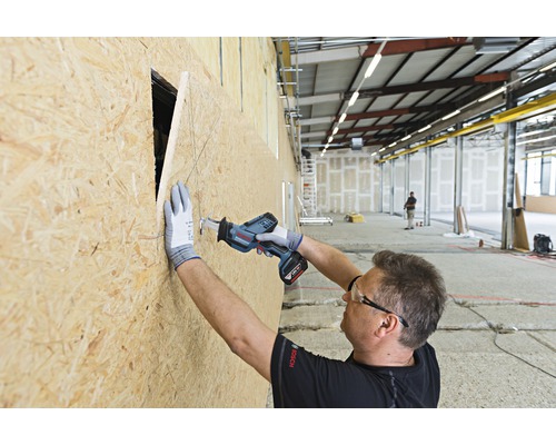 Handwerker sägt mit einer Akku-Säbelsäge ein Loch in eine Holzplatte.
