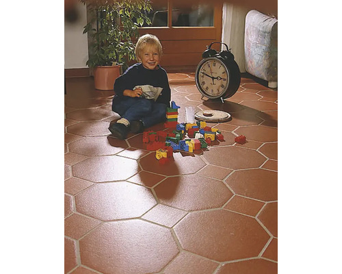 Kind spielt mit Bauklötzen auf einem Boden mit achteckigen Fliesen