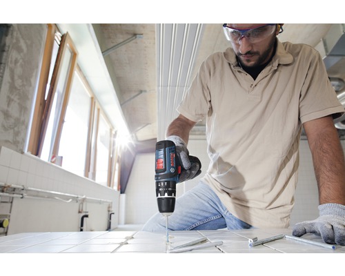 Handwerker bohrt mit einem Akku-Bohrschrauber ein Loch in eine Fliese