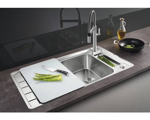 Edelstahlspüle mit Schneidebrett und Armatur auf einer Arbeitsplatte