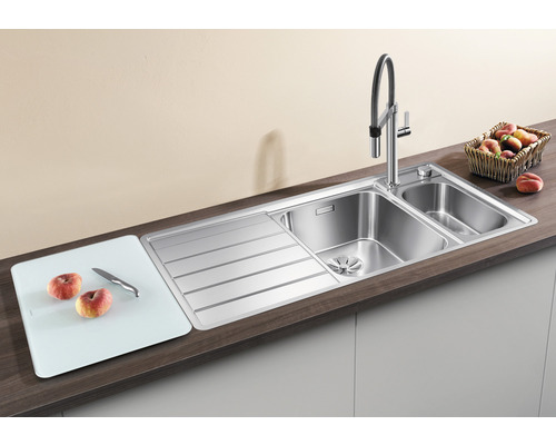 Spüle aus Edelstahl mit Abtropffläche und Schneidebrett auf einer Arbeitsplatte