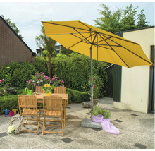Gelber Gartenschirm über Holztisch und Stühlen im Garten