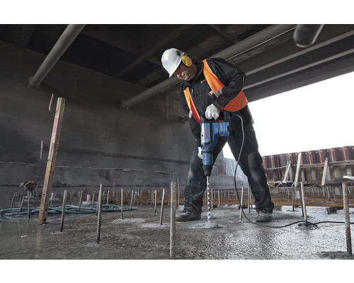 Ein Bauarbeiter bohrt mit einem Bohrhammer in Beton