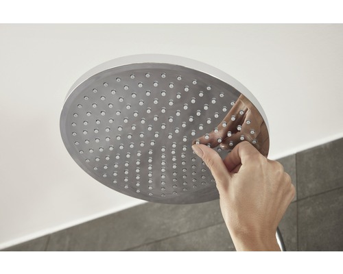 Hand reinigt Duschkopf mit Antikalkfunktion.