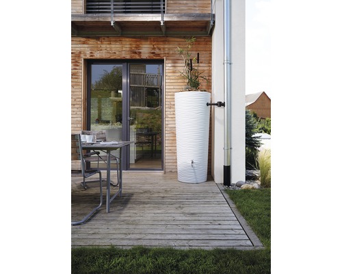 Szene mit einem weißen Wasserbehälter auf einer Holzterrasse neben einem Haus.