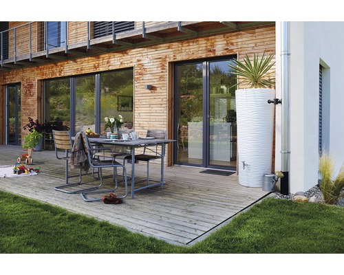Terrasse mit Esstisch, Stühlen und dekorativem Regenwassertank